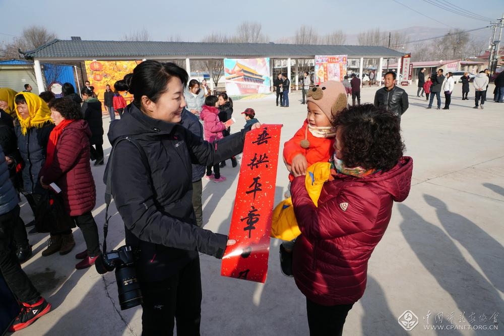3.居杨（左）向陇城镇村民赠送春联。胡建忠摄.JPG